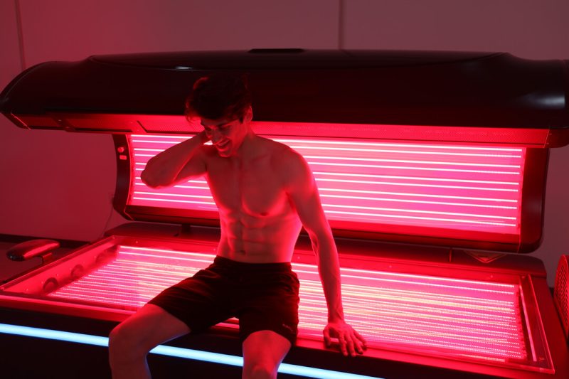 Person using red light therapy device.